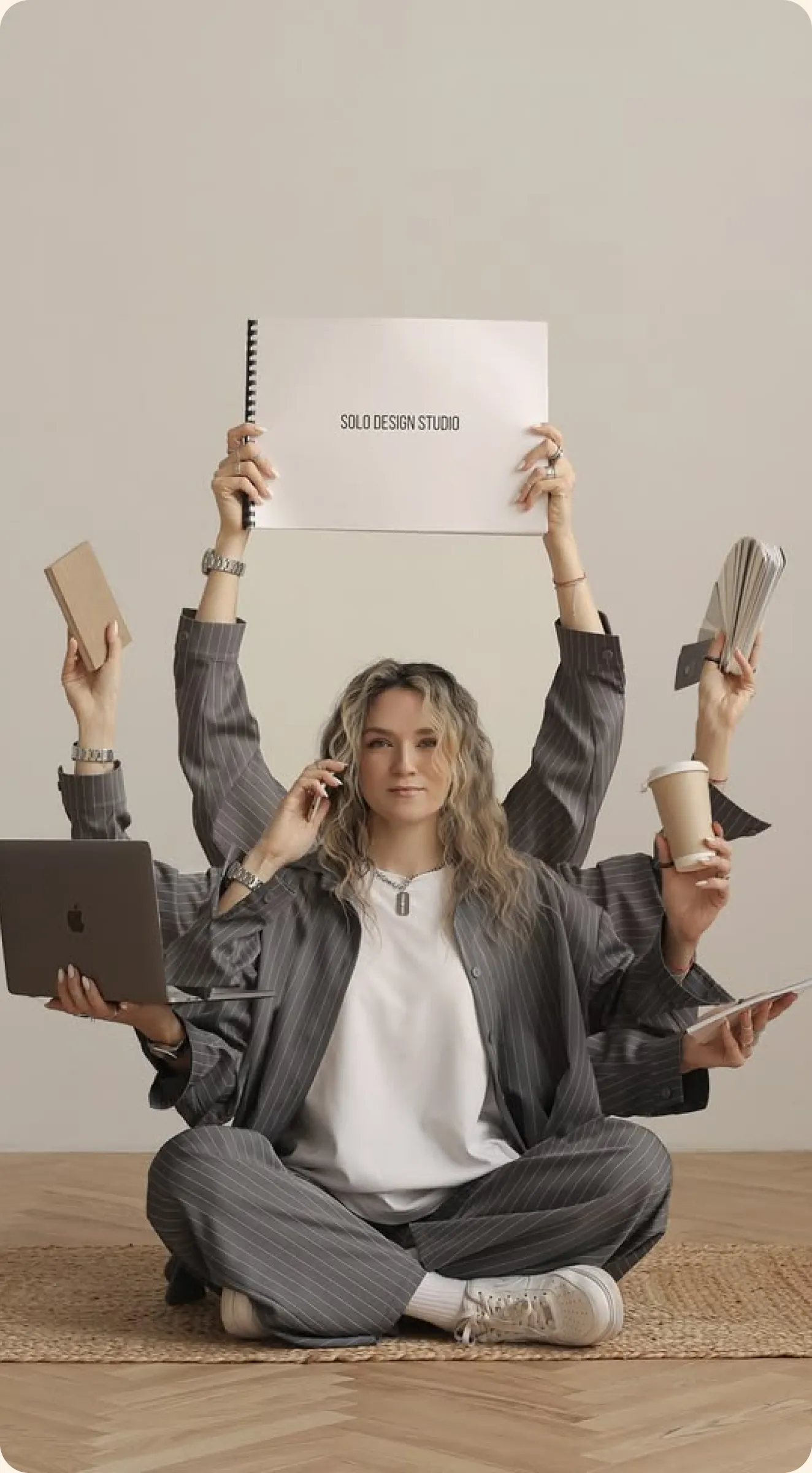 Woman in a suit with multiple arms holding design tools and devices